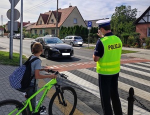 policjant, obok dziecko na rowerze