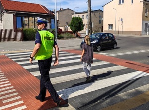 policjant przeprowadzający ucznia przez przejście dla pieszych