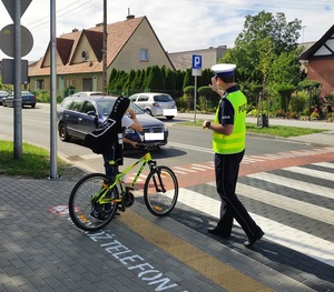 policjant i obok stojący uczeń z rowerem