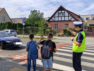 policjant i obok stojący dwójka uczniów