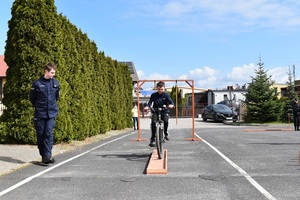stojący policjant i jadący uczeń na rowerze