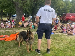 policjant odwrócony plecami z psem służbowym w tle grupa dzieci