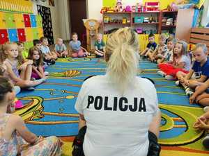 siedząca tyłem do zdjęcia policjantka przed nią grupa dzieci