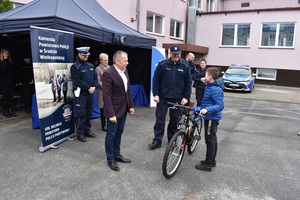 uczeń stojący z rowerem obok starosta średzki i policjant
