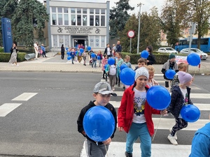 dzieci idące przez przejście dla pieszych z balonami