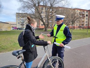 Policjant przekazujący rowerzystce odblask