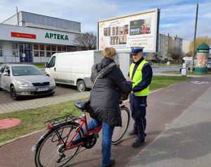 Policjant przekazujący odblask rowerzystce