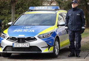 Policjant stojący obok nowego radiowozu.