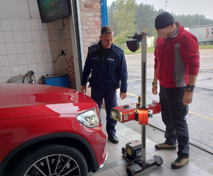 mężczyzna kontrolujący oświetlenie pojazdu, obok stojący funkcjonariusz policji