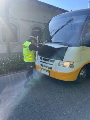 policjant zaglądający pod maskę autobusu