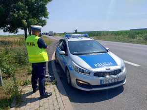 policjant stojący z radarem przy radiowozie