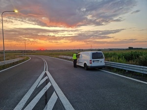 policjant podczas kontroli drogowej stoi przy samochodzie osobowym