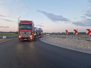 policjant podczas kontroli drogowej stoi przy samochodzie cieżarowym