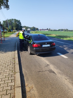 policjant stojący przy samochodzie osobowym