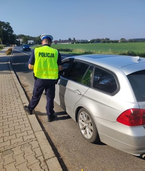 policjant stojący przy osobowym samochodzie