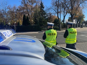 dwóch policjantów stojących przed radiowozem