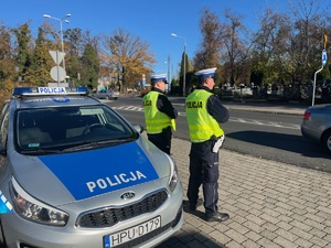 dwóch policjantów stojących przed radiowozem